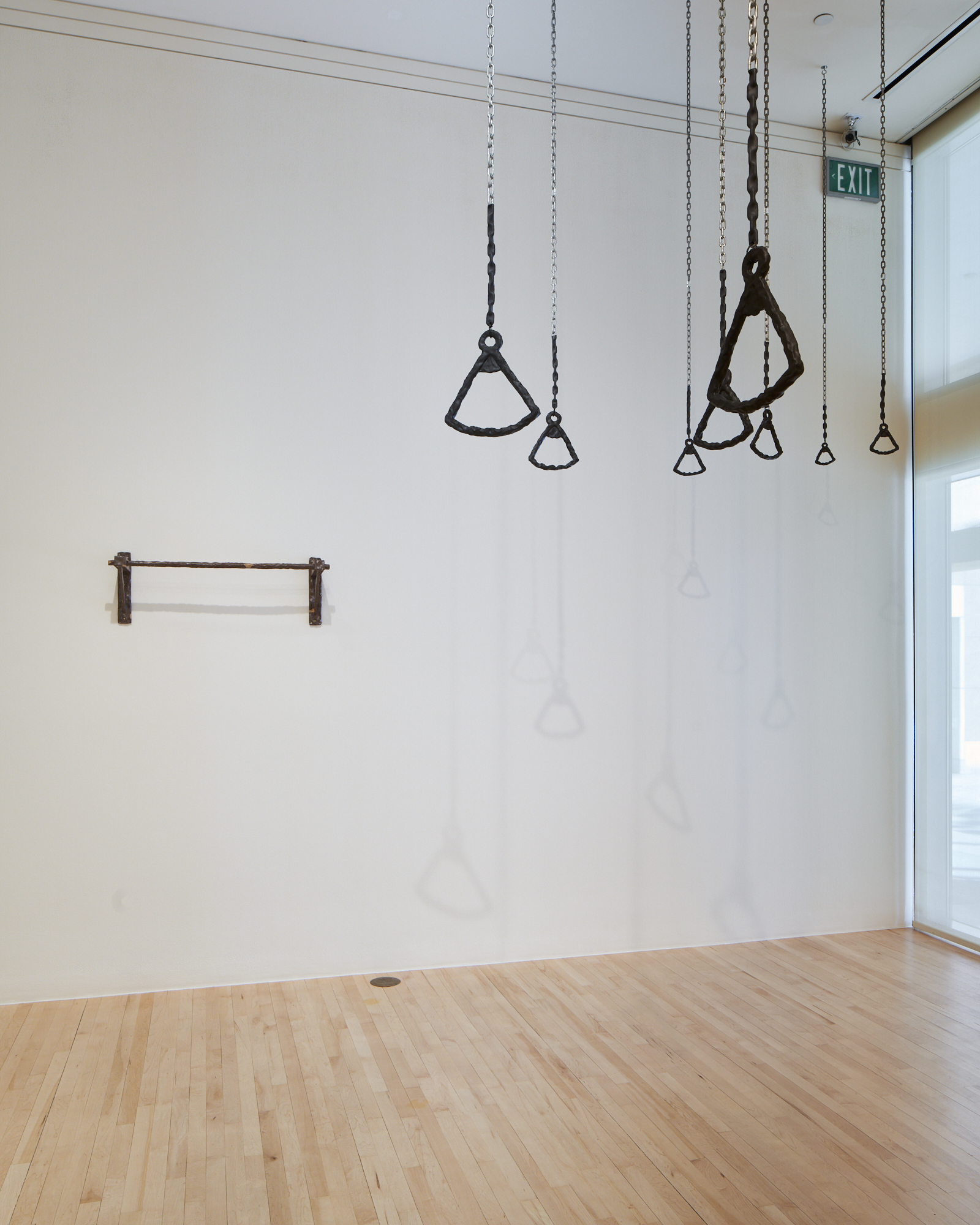 Image of eight gymnastics rings hanging from the ceiling of a dimly lit room with a small window